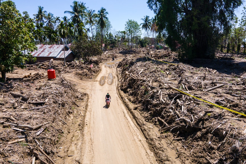 A man riding a motorcycle past the flood damage in Aceh province.