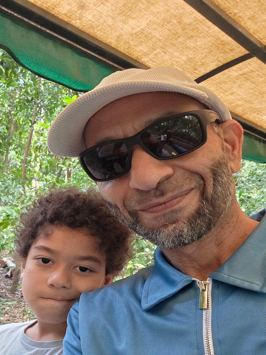 Ahmed and his son smile at the camear