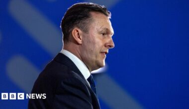Russell Findlay, who has short black hair, in profile against a blue background. He is wearing a business suit