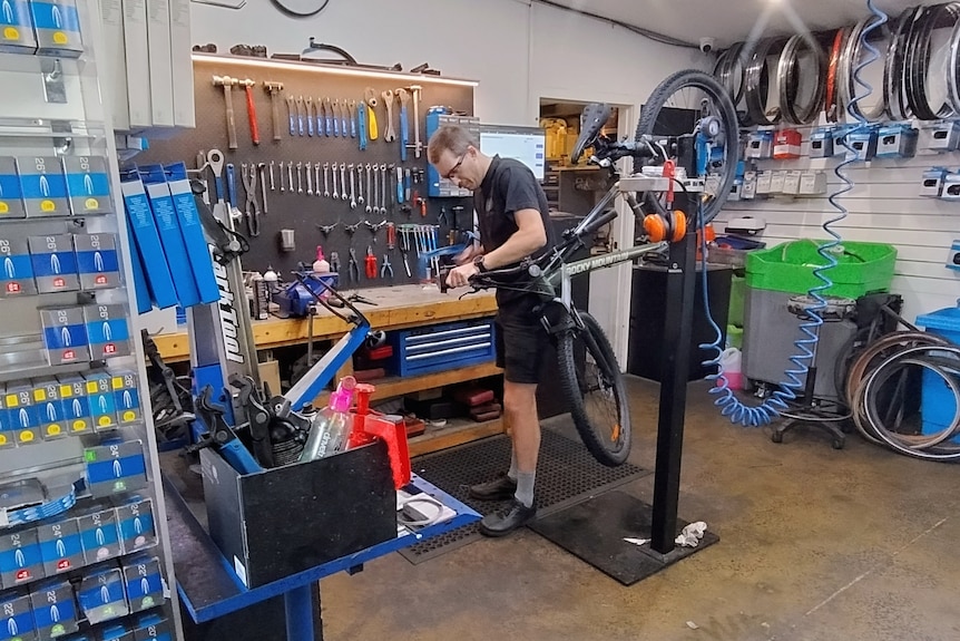A man fixing a bike in a workshop.