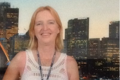 Maree Crabtree smiles as she stands with city buildings behind her.