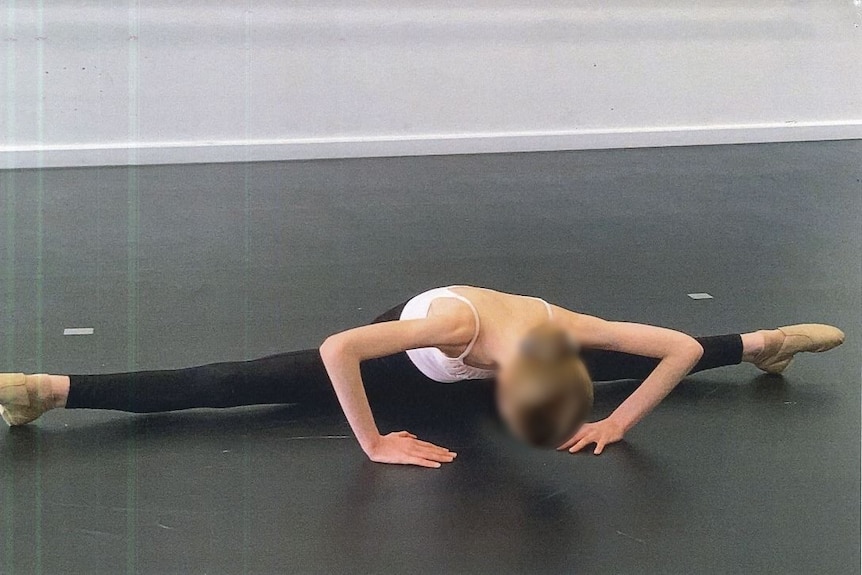 Girl with blurred face dancing in a red tutu with elaborate gold embroidery