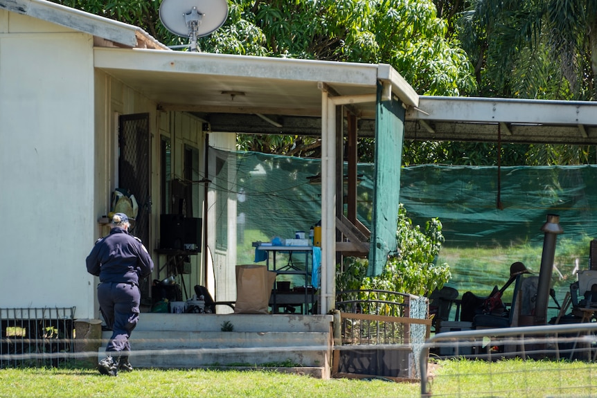 A police officer walking into the front step of an old-looking house.