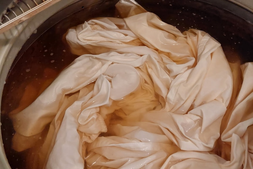 Photo of sheets in the wash, filled with brown water
