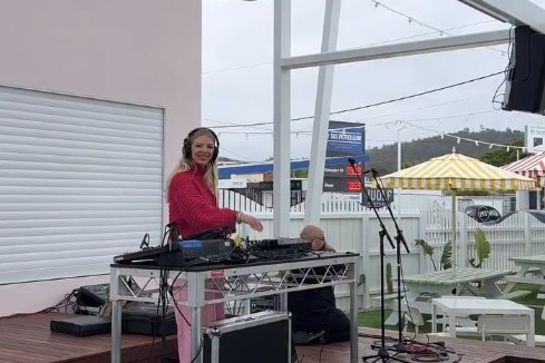 a woman with headphones at a sound mixing desk on an open air stage