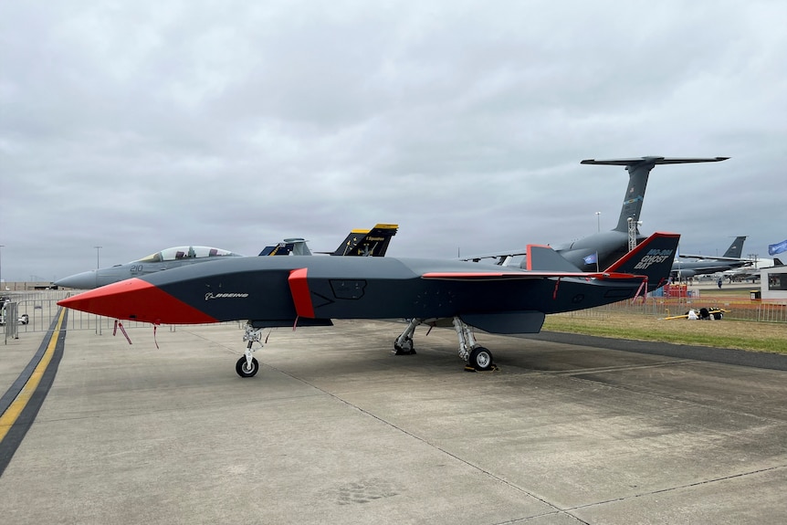 A large drone resembling a pointt uncrewed jet sitting on a tarmac.  