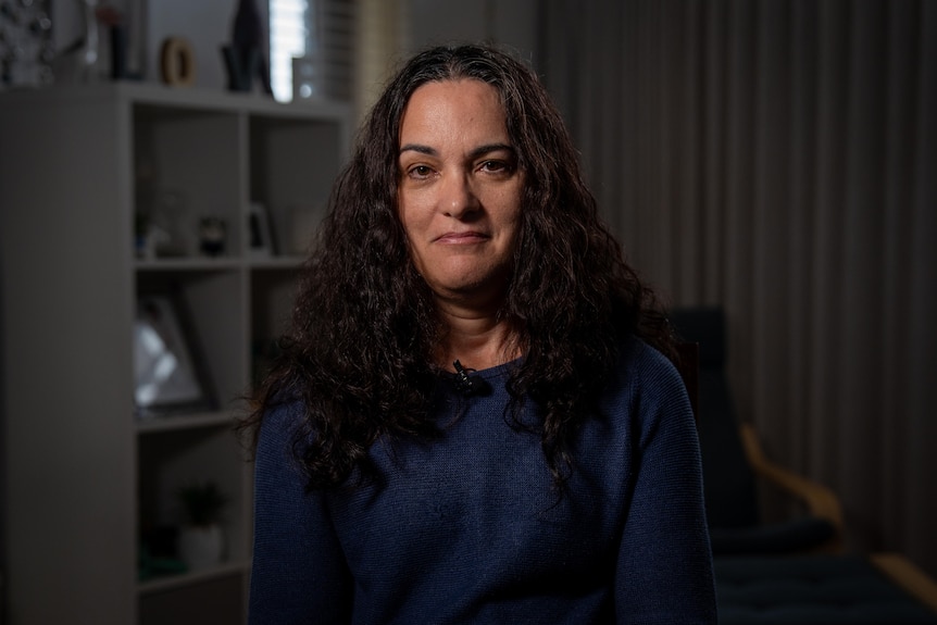 a woman with brown hair sits posed in front of the camera