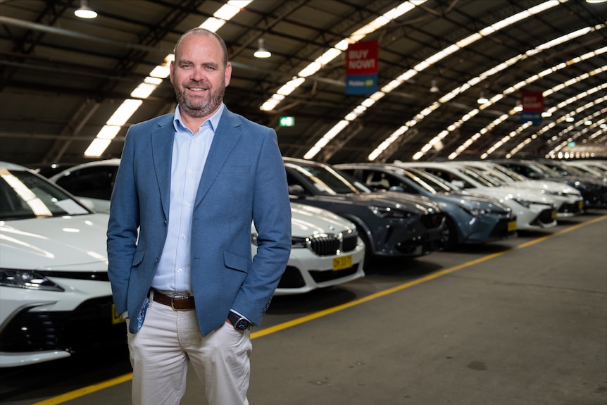 Brendon Green Pickles stands in front of a row of EVs, April 2026.