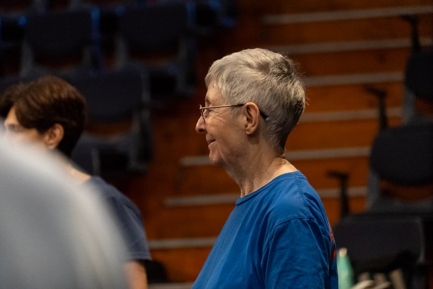 A woman in a blue shirt with grey hair shot in profile.