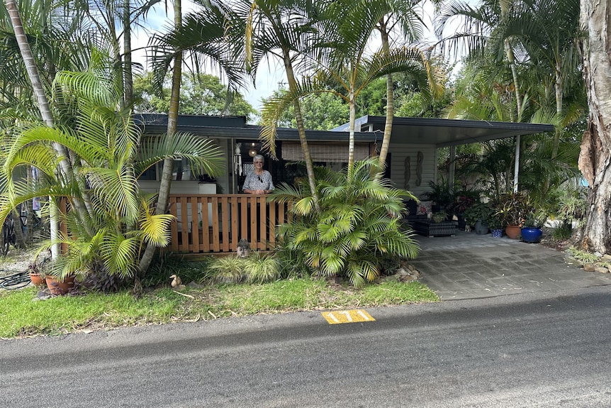 woman standing on deck of home surrounded by palm trees