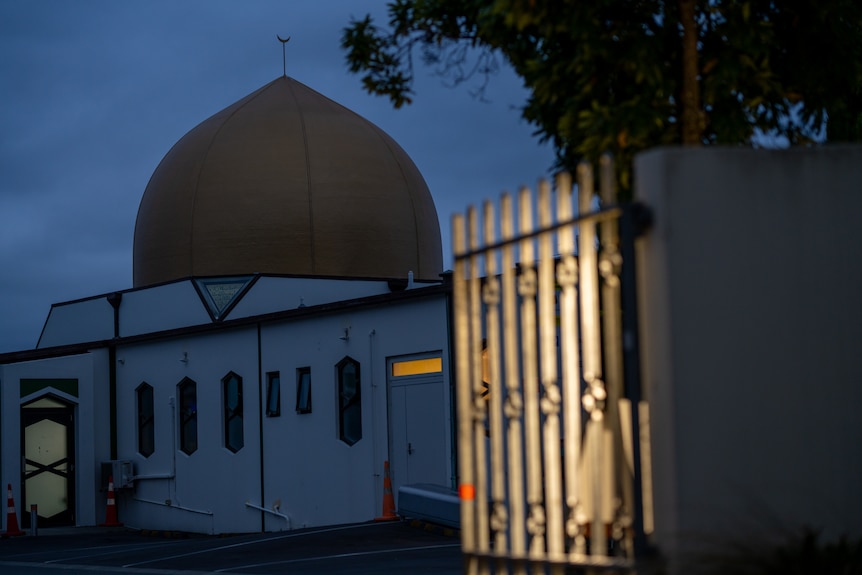 A mosque at night, with light from an outdoor lamp shining on a fence at the entrance to the mosque.
