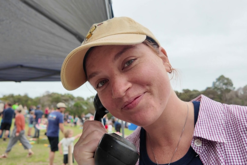 A young woman holds an old telephone receiver to her ear