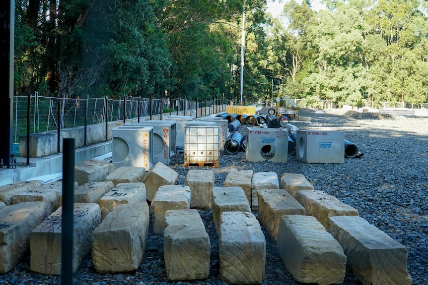 building materials organised outside on a gravel-covered football field