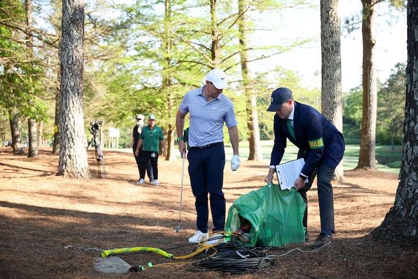 Rory McIlroy stands by as an official moves a generator at the Masters.