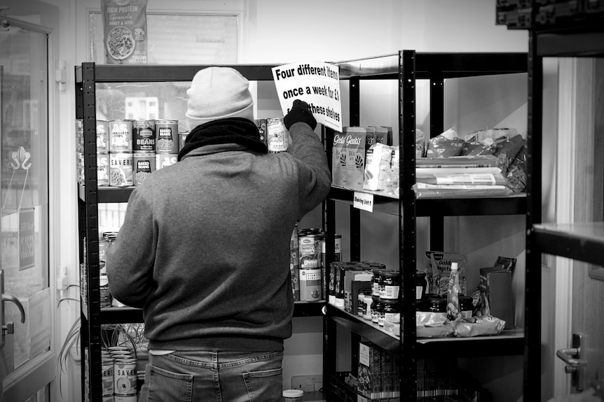 A person going through items on shelves.