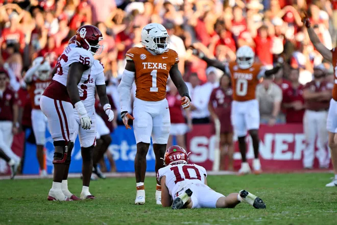 Oct 11, 2025; Dallas, Texas, USA; Texas Longhorns defensive end Colin Simmons (1) stands over Oklahoma Sooners quarterback John Mateer (10) after Mateer is sacked during the second half at the Cotton Bowl. Mandatory Credit: Jerome Miron-Imagn Images