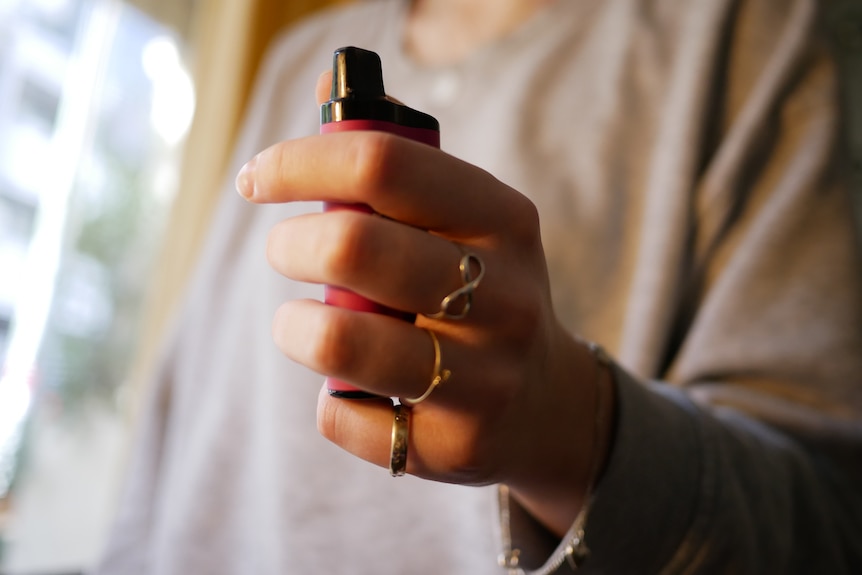 An image of a teenager's hand holding a vape.