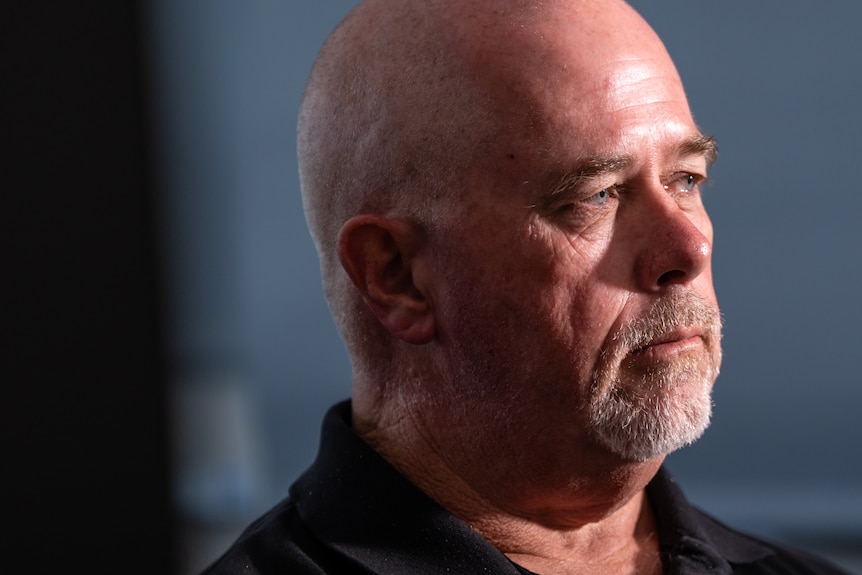 A man in profile looks to the right of screen