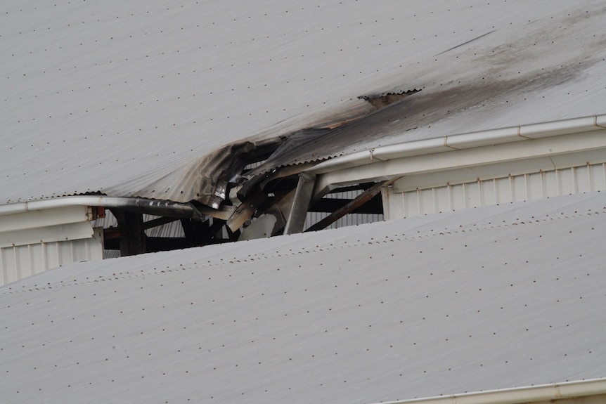 A hole and scorched marks on a wide steel roof
