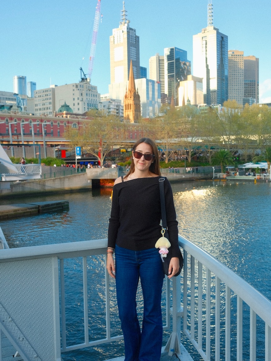 Tara standing on a bridge by a river.