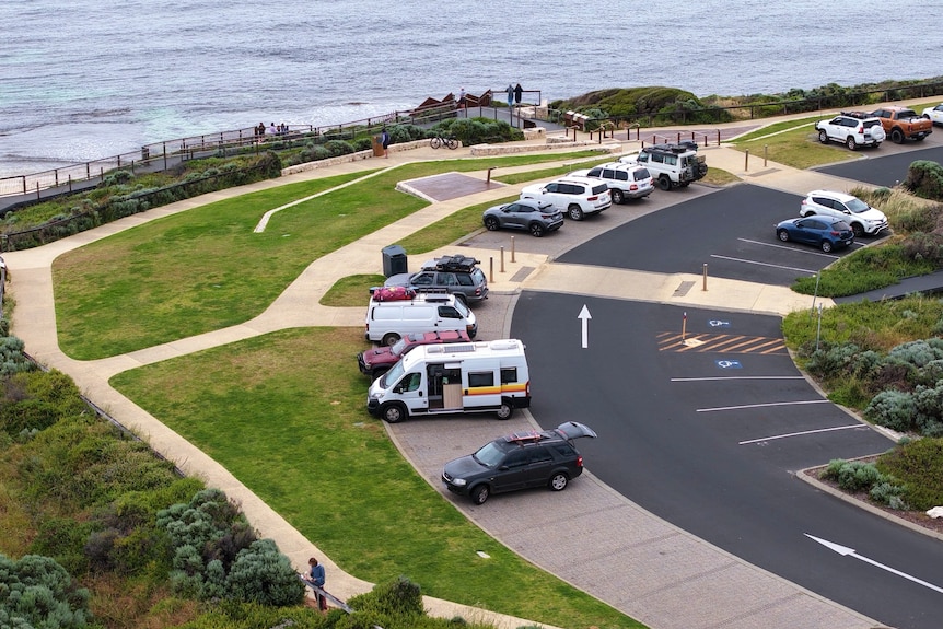 Vans and cars parked at Surfer's point during the day.