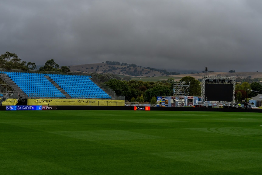 grey clouds above an empty footy stand and green oval