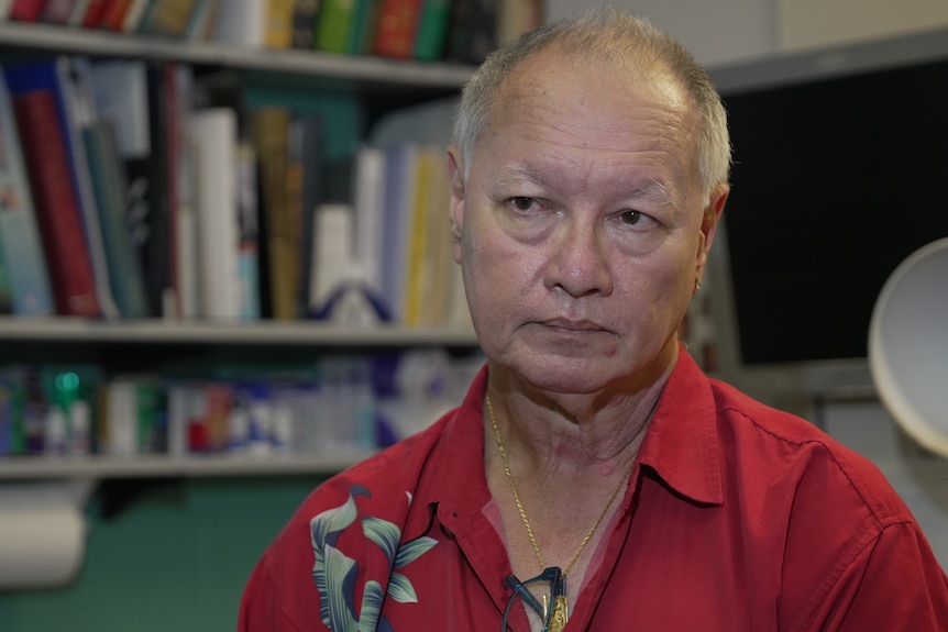 A man seated for an interview, listening to a journalist off-screen.