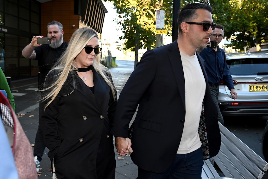 A man and woman leave court wearing dark glasses.