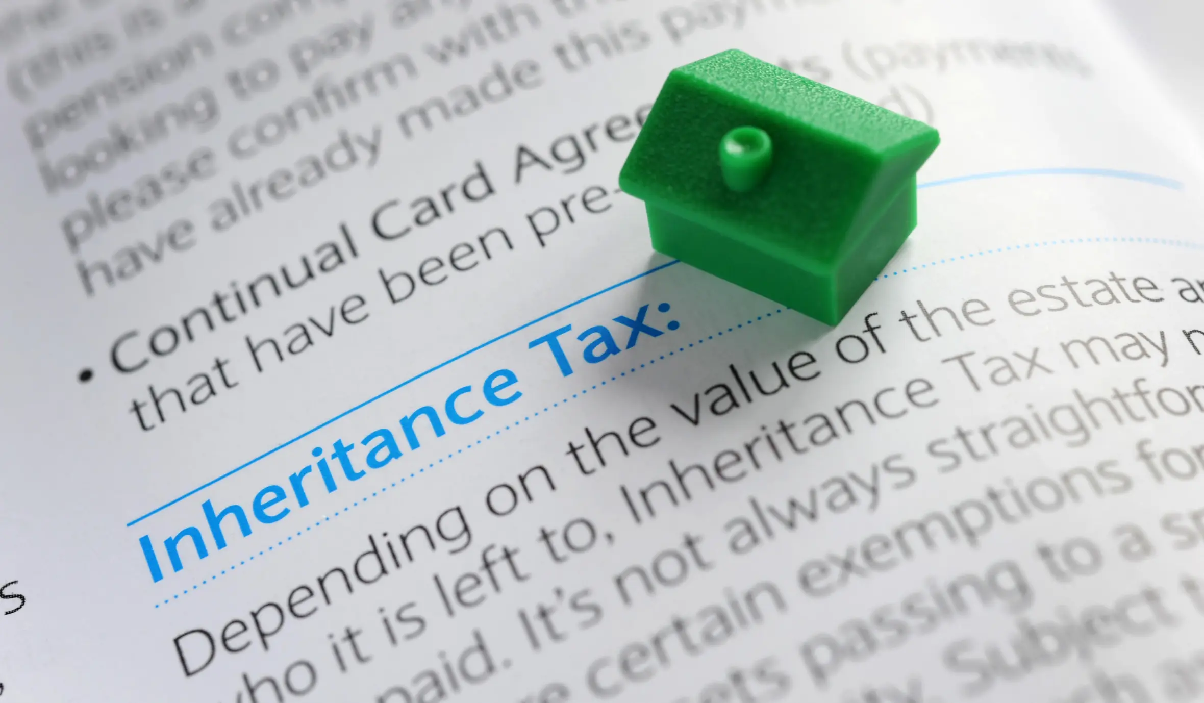 A small green house model on a document with the heading "Inheritance Tax".
