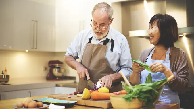 A senior man and woman cooking in kitchen in their house to save money on food costs.