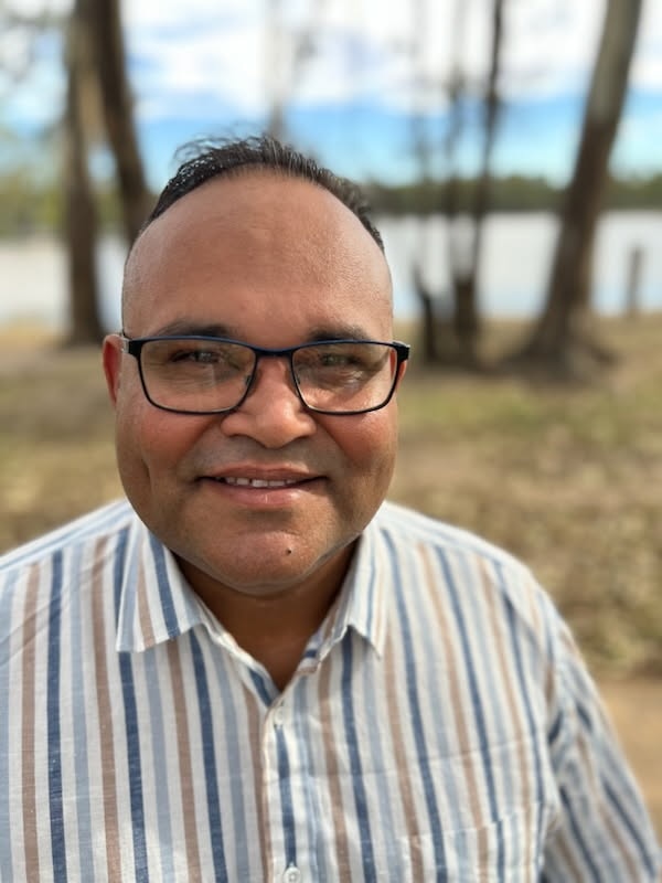 A man with glasses on the bank of a river