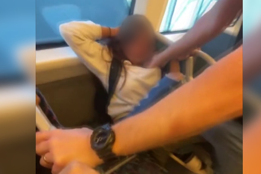 A young girl holds her head and winces with her face being blurred. 