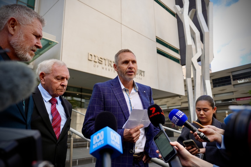 Shane Cable speaks on courthouse steps as his father Barry watches on. 