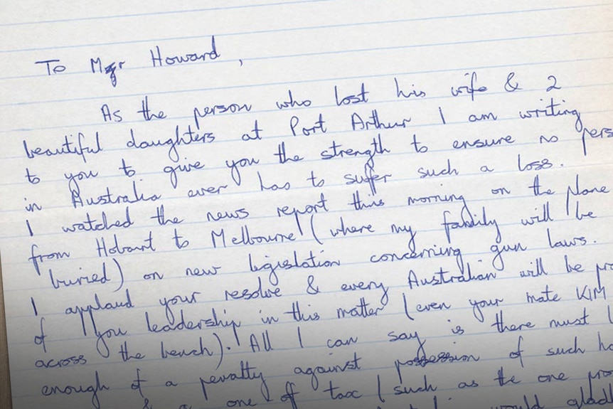 A hand-written letter on a sheet of paper sits on a desk.