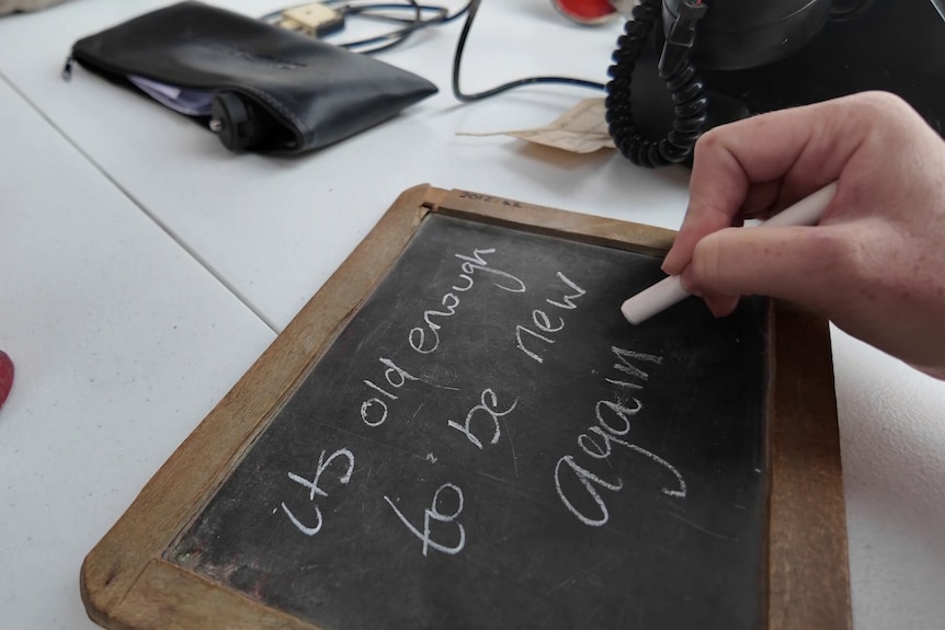 A hand writes on a chalkboard