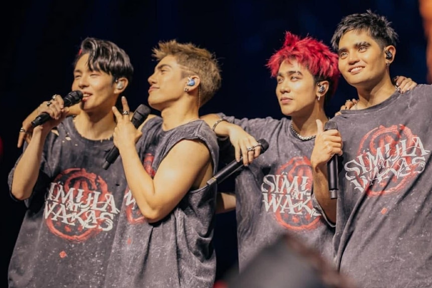 A group of singers with their arms around each other on stage. 