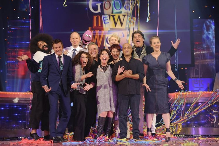 A TV still of a group of comedians, including Paul McDermott, and a purple puppet, on stage, covered in confetti.