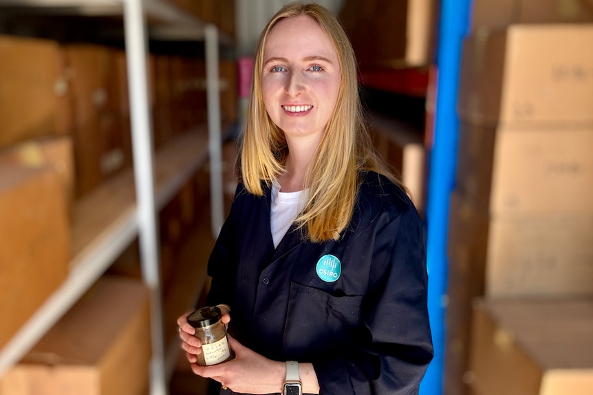 A woman smiles as she holds a sample of soil.