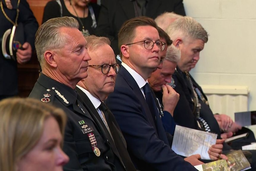 Anthony Albanese seated at a funeral service beside Victoria Police Commissioner Mike Bush