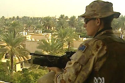 An Australian soldier stands guard in Iraq with a gun in his hand.
