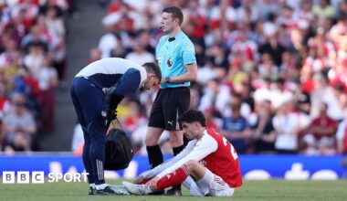 Kai Havertz sits on the pitch while a physio stands over him after injuring himself against Newcastle
