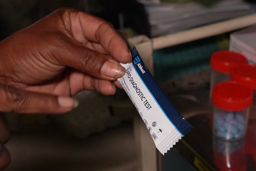 A woman holds a small, unused rapid test for HIV in her hand in a laboratory setting