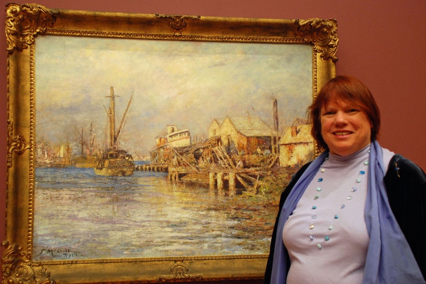 A woman stands next to a painting.