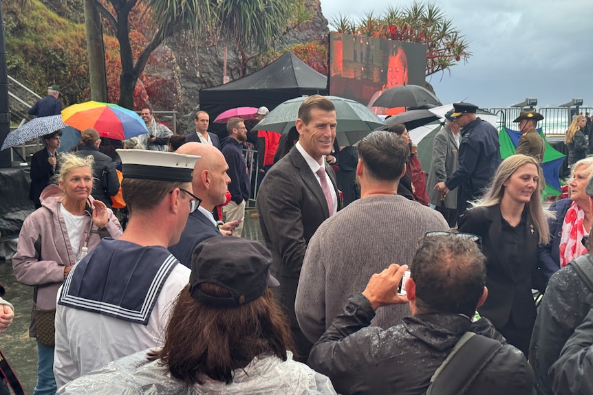 Ben Roberts-Smith shakes hands with supporters in a crowd on a rainy day. 