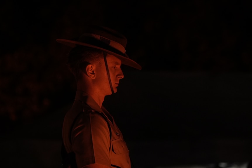A soldier looking down in low light. 