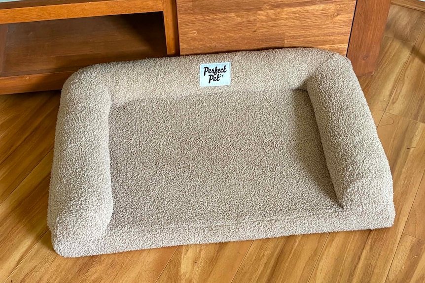 An empty dog bed that says 'perfect pet' on it. 