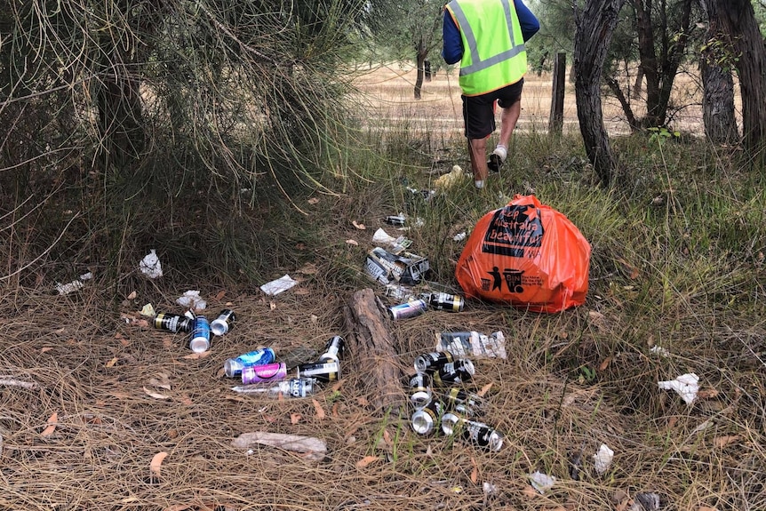 A man walks through a pile of cans in the bush