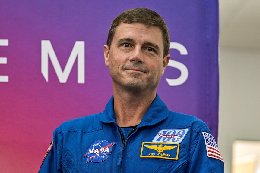 Reid Wiseman smiling and wearing a NASA suit