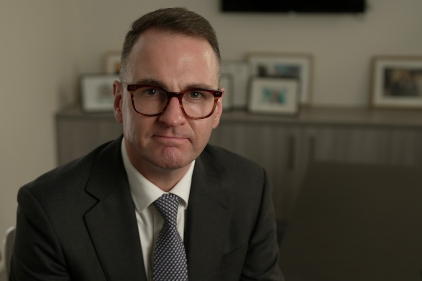 Andrew Bragg wearing a suit sitting inside an office.