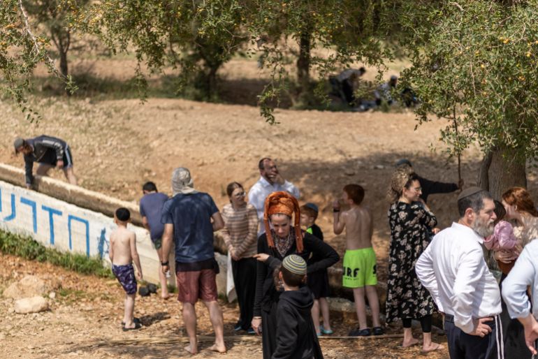 Israeli settlers stand at a water slide in the Israeli-occupied West Bank village of Ras Ein al-Auja on April on April 9, 2026. Israel vowed more strikes against Hezbollah on April 9, dismissing mounting international demands that the fragile truce between the United States and Iran in the Gulf be expanded to cover the war in Lebanon. (Photo by Ilia YEFIMOVICH / AFP)
